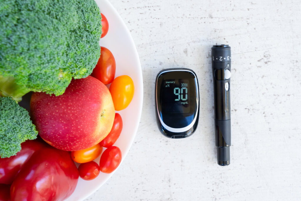 plate of raw vegetables with blood glucose meter and lancet close up, diabetes healthy diet concept